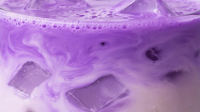 Macro side view of trendy iced ube latte with ice cubes, vibrant purple wellness drink. Trendy and aesthetic coffee shop beverage made from purple yam, associated with superfood trends and refreshi