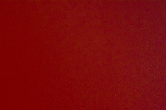 Abstract background of a rough wooden surface painted in deep terracotta burgundy color. Textured matte finish of a red timber door background