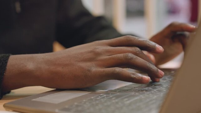 Black hands typing laptop prototype interface, UX designer testing mockup, studio lighting, deliberate gestures on keyboard and trackpad, collaboration notes visible, creative workflow