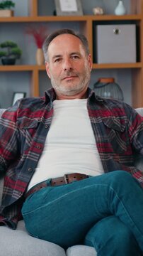 Portrait of relaxed middle eastern man looking at camera sitting on couch. Satisfied retired man with sitting on sofa at home. 4k