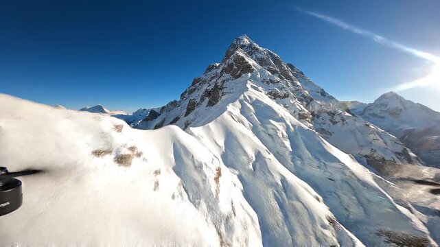 Aerial view flying over picturesque mountain ridge snowy rock texture sun light blue sky landscape. FPV sports drone empty alpine scenery winter glacier freeze valley natural cliff range freeze summit