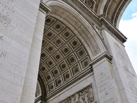 A low-angle, medium shot captures the ornate stone vaulting underneath the
iconic Arc de Triomphe in Paris, France. The composition highlights the
beautiful coffered ceiling filled with sculpted roset