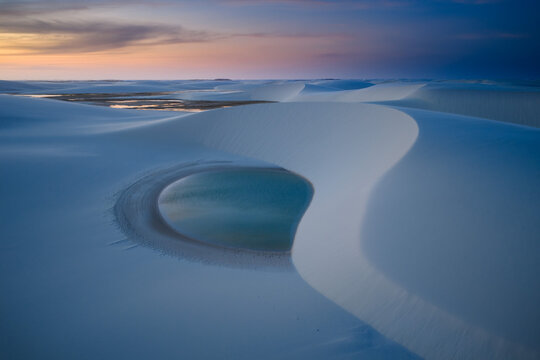 Aerial view of the white sand dunes and turquoise lagoons of Parque Nacional dos Lencois Maranhenses during a soft sunset Lencois Maranhenses, MA, Brazil.