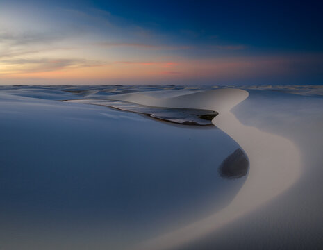Aerial view of Parque Nacional dos Lencois Maranhenses with white sand dunes and freshwater lagoons under a sunset sky Lencois Maranhenses, MA, Brazil.
