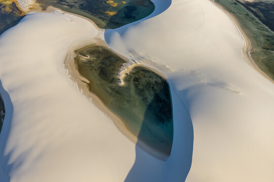 Aerial view of Parque Nacional dos Lencois Maranhenses featuring vast white sand dunes and crystal clear freshwater lagoons under soft sunlight Lencois Maranhenses, MA, Brazil.