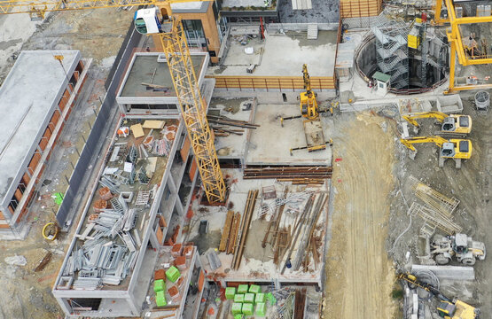 Aerial view of a busy construction site featuring yellow cranes, excavators, and concrete building foundations under development Avcilar, Istanbul, Turkiye.