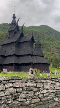 Borgund Stave Church in Norway, an outstanding example of medieval wooden architecture, surrounded by lush greenery and historic gravestones in a peaceful cultural landscape