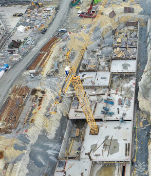 Aerial view of a busy construction site featuring a large yellow tower crane, concrete foundations, and organized building materials in Avcilar, Istanbul, Turkiye.