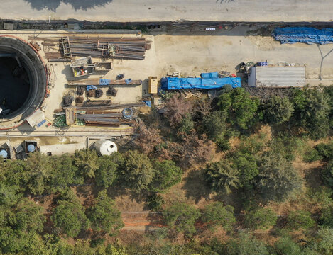 Aerial view of a construction site featuring a large circular excavation shaft and building materials next to a lush green forest in Avcilar, Istanbul, Turkiye.