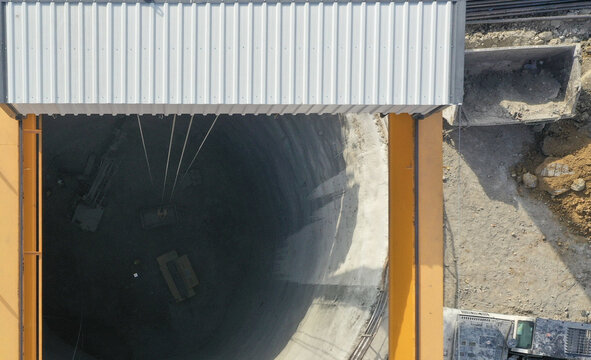 Aerial view of a deep circular construction shaft with a gantry crane and excavation equipment at a building site in Avcilar, Istanbul, Turkiye.