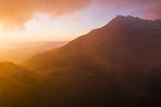 Aerial view of the rugged mountain peaks of Cerreto Laghi enveloped in golden mist and warm sunset light Cerreto Laghi, Emilia-Romagna, Italy.