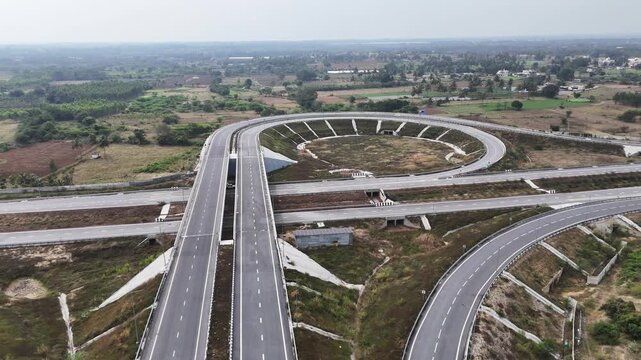 Drone shot capturing the Chennai&ndash;Bengaluru Expressway showcasing structured highway engineering, wide lanes, interconnected flyovers, and geometric road patterns stretching across rural terrain.