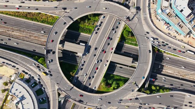 Busy urban roundabout with cars and vehicles moving through a complex multi-level road interchange, showcasing modern infrastructure, transportation systems, and city traffic patterns