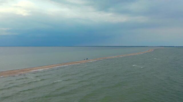 Aerial view of tourists walking along the narrow Mewia Rewa sandbar in the middle of the Baltic Sea.