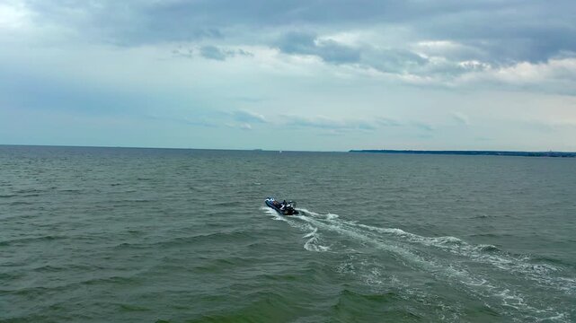Inflatable boat navigating shallow waters around Mewia Rewa sandbar. Drone follows RIB vessel exploring picturesque bay during summer in Poland.