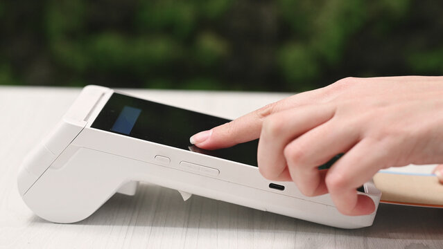 wireless payment terminal in beauty salon and woman paying for a service, enter PIN code, inserts card into POS terminal, closeup. payment by card, cashless payment