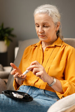 Senior woman monitoring blood glucose level at home