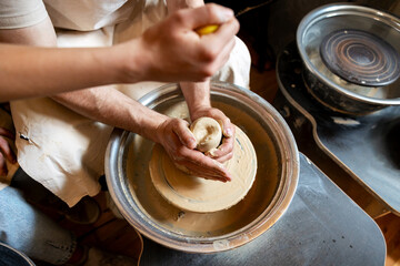 Fototapeta premium Potter's hands molding clay on a spinning wheel
