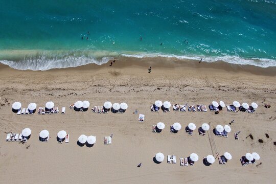 Aerial view of Singer Island beach with turquoise water, white umbrellas, and people relaxing on the sand Riviera Beach, Florida, United States.