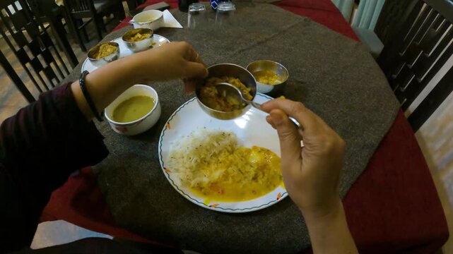 POV of Woman Eating Traditional Indian Thali Meal at Dining Table
