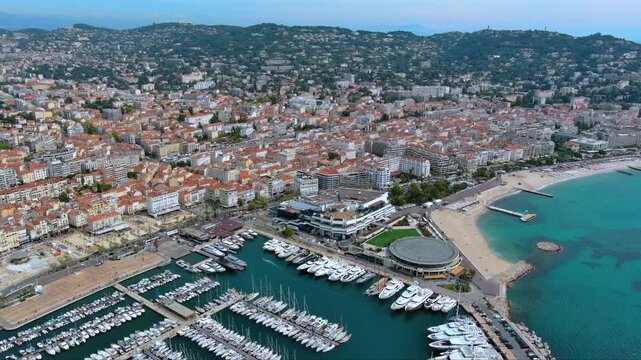 4K aerial view of Vieux Port de Cannes with hundreds of moored yachts, Palais des Festivals, Croisette beach, All&eacute;es de la Libert&eacute; and Esterel hills in the background, France.
