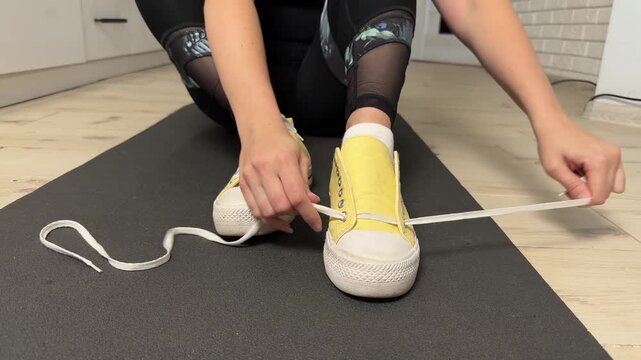 Woman Methodically Demonstrating How To Tie Sneakers Correctly In Casual Fitness Environment