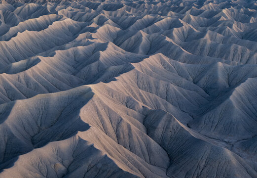 Aerial view of the intricate patterns of eroded badlands and sharp ridges under soft twilight in Hanksville, Utah, United States.