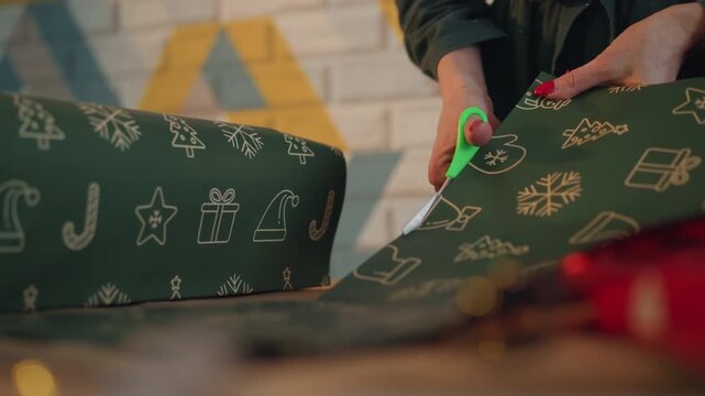 Closeup christmas present cutting green paper, hands trim patterned sheet with scissors, steady motion and bokeh lights, red nails, studio lighting, precise edge alignment, focused holiday preparation