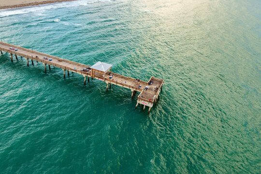 Aerial view of Deerfield Beach International Fishing Pier with people fishing over turquoise ocean water in Deerfield Beach, Florida, United States.