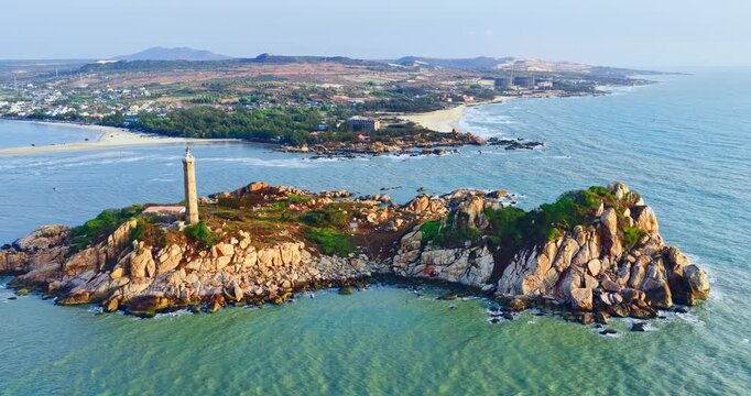 Aerial morning view of Ke Ga Lighthouse in Binh Thuan, Vietnam, surrounded by rocky islands, turquoise seawater, and peaceful coastal landscape