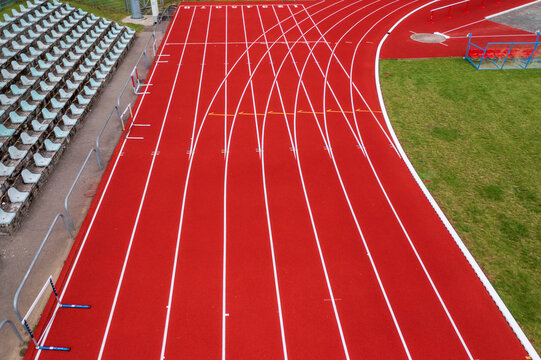 Aerial view of a red running track with white lane markings and stadium bleachers in Vilnius County, Lithuania.