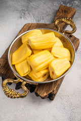 Sweet, golden jackfruit pods (bulbs) in a traditional metal bowl with a fork. Exotic tropical snack or dessert with copy space © Mironov