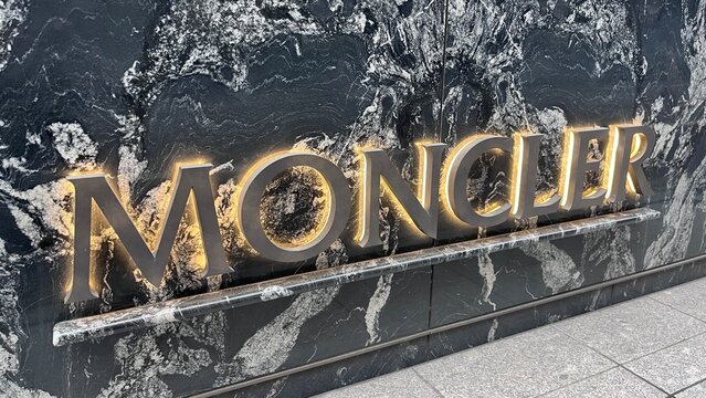 Moncler luxury fashion boutique signage featuring illuminated metal 3D lettering on a decorative black marble wall at the Mikimoto Ginza 2 building - Tokyo, Japan, October 16, 2025