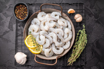 Fototapeta premium Uncooked prawns shrimps ready for gourmet cooking. Dark, moody shot with citrus and herbs. Negative space for text.