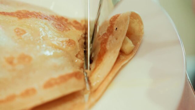 Detailed pastry closeup. Crispy crepe revealing filling details. Close image capturing texture and sheen of dessert. An intimate view of crepe pastry with filling and glossy syrup finish