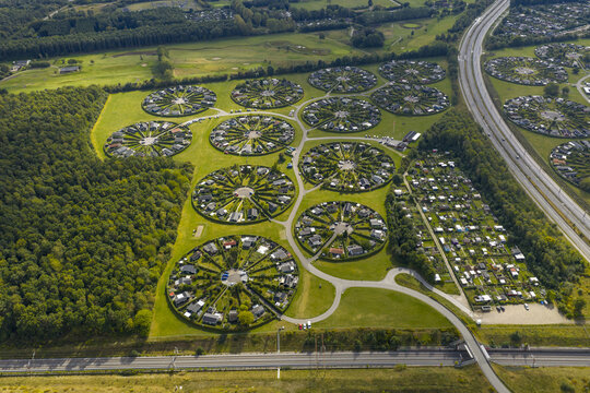 Aerial view of the unique circular allotment gardens of Haveforeningen Harekaer with green hedges and small houses near a forest and highway in Brondby, Denmark.