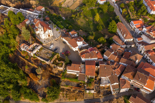 Aerial view of the historic village of Coja featuring the parish church and traditional terracotta rooftops surrounded by lush greenery in Coja, Coimbra District, Portugal.