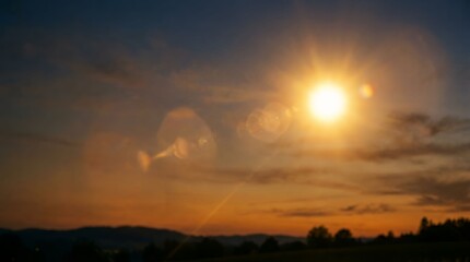 Obraz premium Sunset over peaceful rural landscape with glowing sun and vibrant sky colors