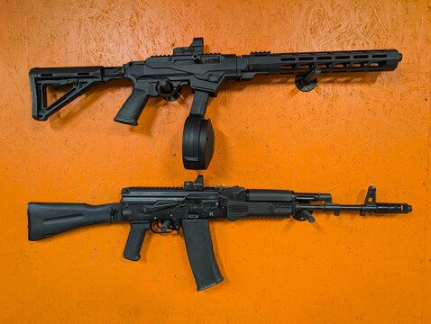 Baltic States - May 15, 2026: Modern civilian firearms featuring a Ruger PC Carbine with a drum magazine and a Saiga AK-style rifle mounted on an orange wall.