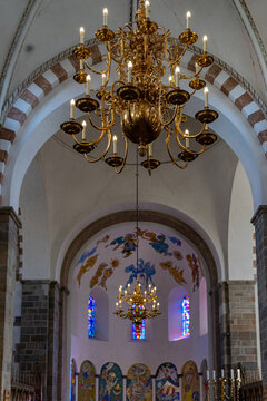 View of the ornate brass chandeliers and colorful frescoes inside the historic Ribe Cathedral with vaulted arches Ribe, Denmark.