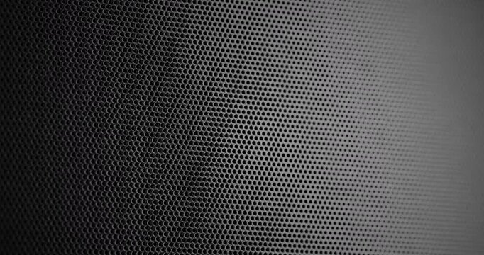 Black Perforated Metal Mesh. Smooth slow movement across extreme close-up of dark perforated metal grid with dramatic side lighting.