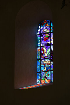 View of the modern stained glass window inside Ribe Cathedral with colorful light reflecting on the stone sill in Ribe, Denmark.