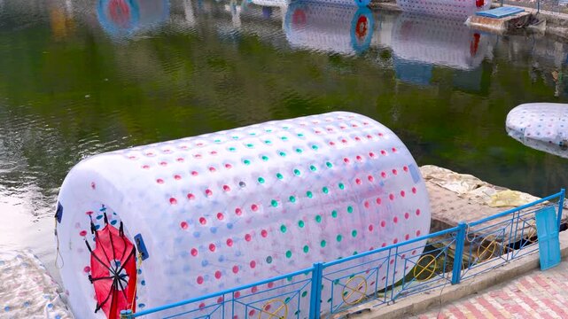 Inflatable water roller ball docked at a lake shore in a recreational activity park, Nainital