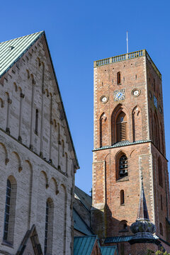 View of Ribe Cathedral featuring the historic red brick bell tower and stone facade under a clear blue sky in Ribe, Denmark.