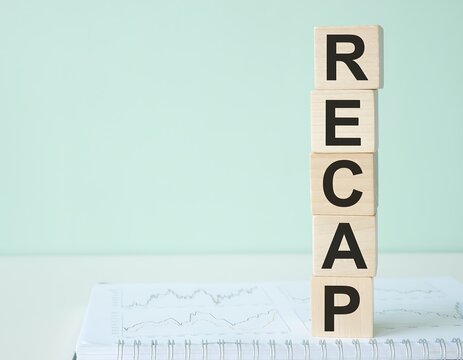 Wooden Blocks Spelling Recap on a White Surface with Green Background.