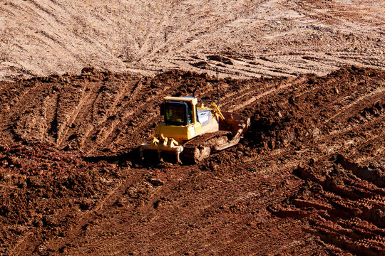 Heavy industrial bulldozer working on massive construction site moving soil