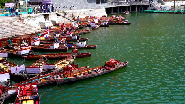 High-angle view of colorful wooden rowing boats docked at a busy mountain lake in Nainital