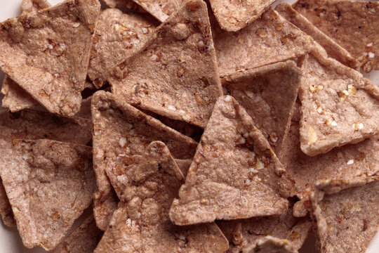 Crispy organic buckwheat nachos with amaranth and quinoa. Triangular tortilla chips with crunchy texture. Gluten-free snack. Top view. 