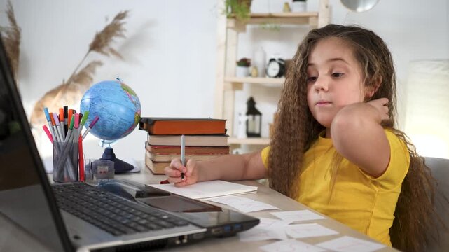 Tired girl student does school homework at desk. Curly girl uses laptop for learning. Tired student feels frustration during study. Difficult homework makes study hard. Education takes effort.