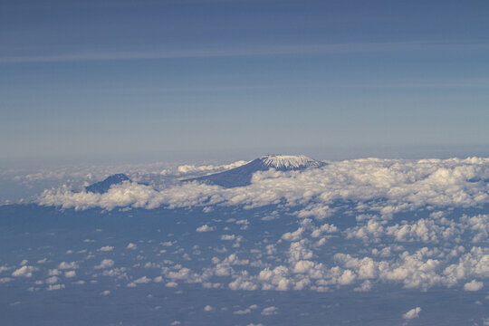 View of the snow-capped peak of Mount Kilimanjaro rising above a dense layer of white clouds under a clear blue sky Tiwi, Kwale, Kenya.